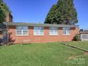 Expansive backyard features a lush lawn, mature trees, and a charming brick exterior with multiple windows at 303 Island Ford Rd, Maiden, NC 28650