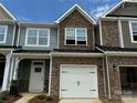 Close-up of a townhome featuring a stone facade, white garage door, and available signage in the window at 6256 Culbert St # 187, Harrisburg, NC 28075
