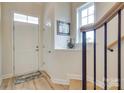 Bright entryway with light hardwood floors, white door, and staircase with black metal railing at 8221 Houser St, Cornelius, NC 28031