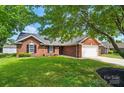 Inviting red brick home featuring a two-car garage, neat landscaping, and classic black shutters at 8309 Emily Dr, Harrisburg, NC 28075