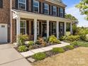 Inviting covered front porch with elegant columns and colorful landscaping along the walkway at 9871 Travertine Trl, Davidson, NC 28036