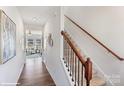 Inviting hallway with wood floors, staircase with wood railing and iron spindles, and a view into the living room at 115 Falling Up Ln, Salisbury, NC 28147