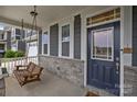 Inviting front porch featuring a wooden swing, stone accents, and a view of the well-manicured front yard at 1601 Calder Dr, Indian Trail, NC 28079