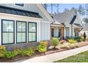 Close up view of a light grey home with a black roof, black window accents, and lush green landscaping at 2396 Lee Lawing Rd, Lincolnton, NC 28092