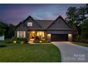 Charming home with a well-manicured lawn, a two-car garage, and inviting front porch at twilight at 3424 Saint Clair Nw Ct, Concord, NC 28027
