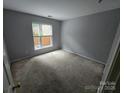 This cozy bedroom offers ample natural light from the window and neutral carpeting at 521 Donatello Ave, Charlotte, NC 28205