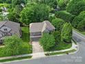 An aerial view shows a brick home with mature trees and landscaping in a residential neighborhood at 5633 Open Book Ln, Charlotte, NC 28270