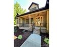 Inviting covered porch with classic lighting and brick accents leading to a beautiful glass front door at 603 Turnberry Ct, Albemarle, NC 28001