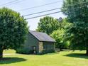 Home with a well-manicured lawn, stone facade, and sunroom, nestled among mature trees at 7728 Babe Stillwell Farm Rd, Huntersville, NC 28078