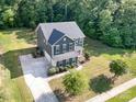 Two-story home boasts a spacious front yard, dark blue siding, a wide driveway, and mature trees at 8268 Breton Way, Harrisburg, NC 28075