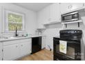 Bright kitchen features white cabinets, black appliances, and a window overlooking a green yard at 116 Barnes Ln, Stony Point, NC 28678