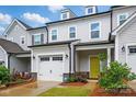 Well-maintained townhome with a one-car garage, welcoming yellow door, and lush landscaping at 12021 Basking Dr, Charlotte, NC 28214