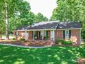 Charming one-story brick home featuring a cozy covered front porch with seating and manicured landscaping at 135 Henry Putnam Dr, Cherryville, NC 28021