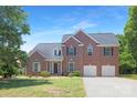 Charming two-story brick home with a well-maintained lawn, attached two-car garage, and classic architectural details at 1465 Porters Ct, Concord, NC 28025