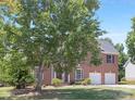 Charming two-story brick home with a well-maintained lawn, attached two-car garage, and classic architectural details at 1465 Porters Ct, Concord, NC 28025