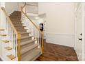 Elegant carpeted staircase with white railing and wooden banister, leading to the second floor, and hardwood floors at 1465 Porters Ct, Concord, NC 28025