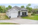 Charming one-story home with light gray siding, black shutters, and a one-car garage at 401 Groves St, Lowell, NC 28098
