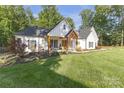 Stylish white farmhouse with attractive landscaping and a welcoming front entrance at 518 Maynard Farm Ln, Stanley, NC 28164