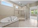 Modern bathroom featuring a soaking tub, glass-enclosed shower, and neutral tile at 709 Cavesson Way, Monroe, NC 28110