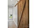 Hallway featuring wood-look flooring, a sliding wooden barn door and backyard access at 945 Westbrook Dr # A, Charlotte, NC 28202