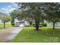 Inviting home featuring a well-manicured lawn and mature trees enhancing its curb appeal at 10016 Lawing School Rd, Charlotte, NC 28214