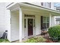 Welcoming front door featuring decorative wreath and sidelights, complemented by charming porch seating at 10016 Lawing School Rd, Charlotte, NC 28214