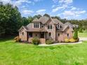 Beautiful two-story home features a stone facade, brick accents, and lush lawn at 1010 Nutall Oak Ln, Belmont, NC 28012