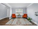 Bright living room featuring hardwood floors, a colorful area rug, two orange chairs and natural light at 10431 Plantain Ct, Charlotte, NC 28213