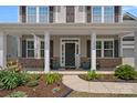 Inviting front porch with stone accents, decorative plants, and a charming entrance, showcasing the home's curb appeal at 10906 Charmont Pl, Huntersville, NC 28078