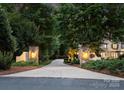 Private tree-lined driveway leading to a stately home with stone gateposts and elegant lighting at 12835 Ninebark Trl, Charlotte, NC 28278