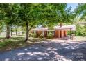 Inviting exterior of a brick home with lush trees and a paved driveway leading to a covered carport at 175 Triplett Rd, Cleveland, NC 27013