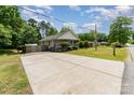 View of the single-story home featuring a long driveway with manicured lawn and shrubbery at 201 Easy St, Concord, NC 28027
