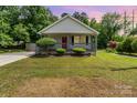 Single-story home featuring a charming front porch, a red front door, and a manicured lawn and shrubbery at 201 Easy St, Concord, NC 28027