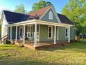 Inviting exterior with expansive porch, classic columns, green siding and a beautiful lawn on a sunny day at 222 Brevard St, Statesville, NC 28677