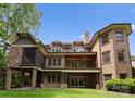 Rear exterior view of a brick house featuring a large balcony and screened porch at 3815 Stoney Ridge Trl, Charlotte, NC 28210