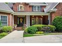 Inviting front porch with decorative columns, seasonal wreath and lush landscaping at 5718 Bardsey Ct, Matthews, NC 28104