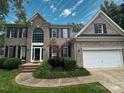 Charming two-story brick home with a well-manicured lawn and attached two-car garage at 7006 Olde Sycamore Dr, Mint Hill, NC 28227