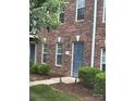 Exterior view of a brick townhouse with a gray front door, manicured bushes, and a tidy mulched walkway at 135 Locomotive Ln # 106, Mooresville, NC 28115