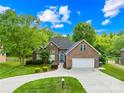 Inviting brick home with lush green lawn, mature trees, and a two-car garage at 229 River Birch Cir, Mooresville, NC 28115