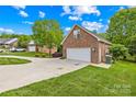 Side view of an attached two-car garage with a long driveway and manicured lawn at 229 River Birch Cir, Mooresville, NC 28115