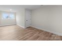 This bedroom has wood-look floors, a window, and a door with neutral-colored walls at 3220 Riley Ave, Charlotte, NC 28269