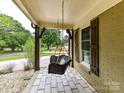 Cozy front porch featuring a hanging wicker chair, stone flooring, and natural wood accents at 4711 Truscott Rd, Charlotte, NC 28226