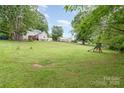 Large grassy backyard, perfect for outdoor activities and entertainment, with mature trees and play structure at 702 S Government St, Lincolnton, NC 28092