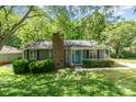 Charming single-story home featuring a brick chimney, a light-blue front door, and lush landscaping at 9021 Louvaine Dr, Charlotte, NC 28227