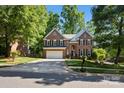 Stately two-story brick home featuring a two-car garage and mature landscaping on a sunny day at 909 Staghorn Ln, Waxhaw, NC 28173