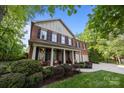 Beautiful brick home featuring a manicured lawn, black shutters, and a charming front porch with rocking chairs at 1108 Longwood Ct, Matthews, NC 28104