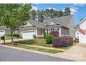 Charming home featuring a two-car garage, tidy lawn, and colorful landscaping, underneath a sunny sky at 2035 Moultrie Ct, Fort Mill, SC 29707