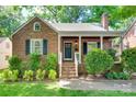 Classic brick house featuring a covered porch, manicured lawn, and inviting entryway, enhanced by neat landscaping at 2124 Chambwood Dr, Charlotte, NC 28205