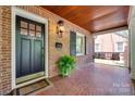 Welcoming front porch features a porch swing, beautiful brickwork, and a charming black front door at 2124 Chambwood Dr, Charlotte, NC 28205