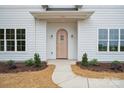 A close-up of the charming wooden front door, framed by elegant sconces and manicured landscaping at 3622 E Brief Rd, Monroe, NC 28110
